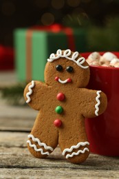 Photo of Tasty gingerbread man cookie and cocoa with marshmallows on wooden table, closeup