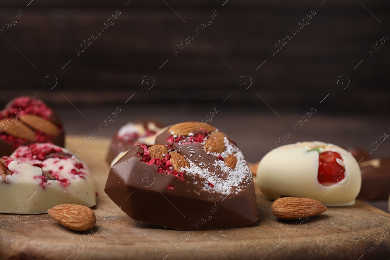 Photo of Tasty chocolate heart shaped candies with nuts, closeup