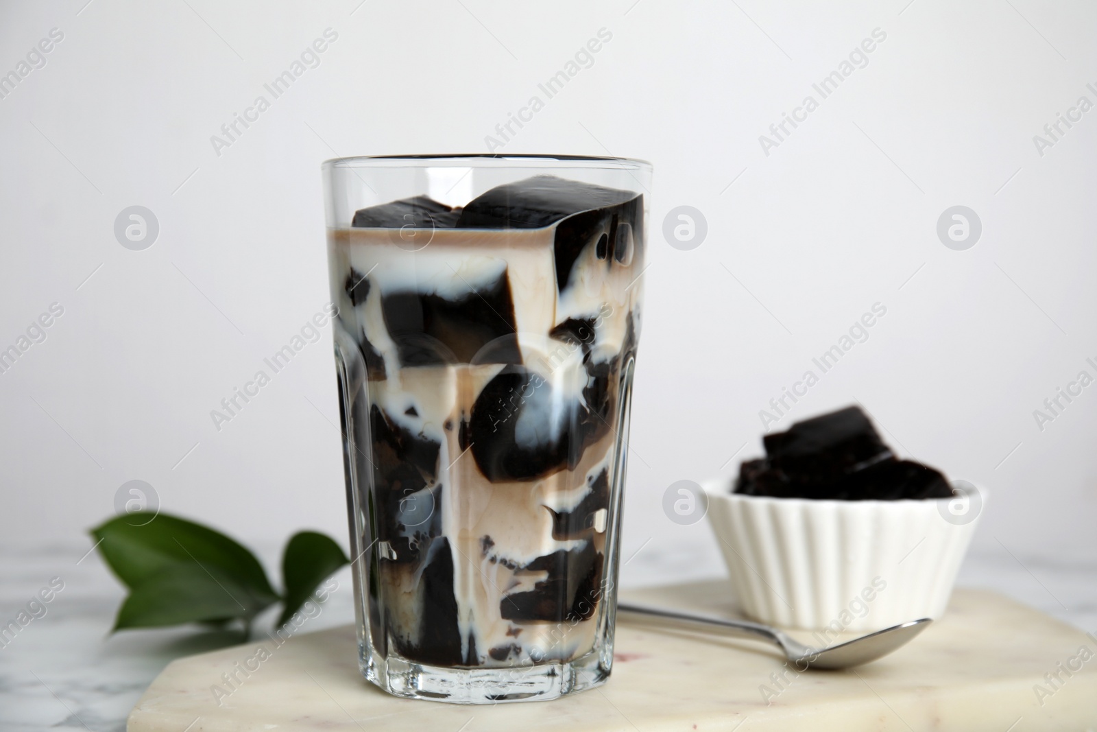 Photo of Glass of milk with grass jelly on table, closeup