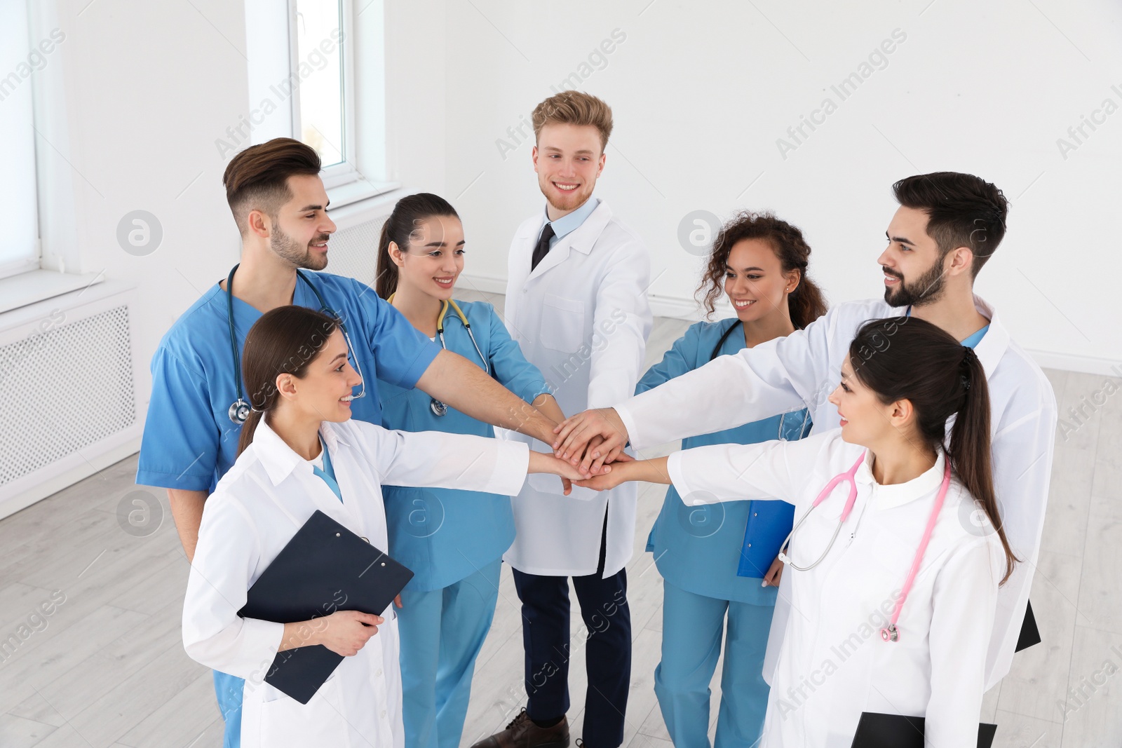 Photo of Team of medical workers holding hands together in hospital. Unity concept