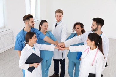 Team of medical workers holding hands together in hospital. Unity concept