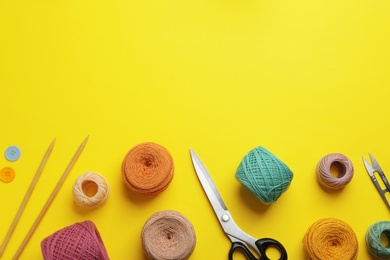 Knitting threads and sewing stuff on color background, flat lay. Space for text