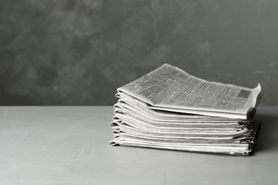 Photo of Stack of newspapers on light grey stone table, space for text. Journalist's work