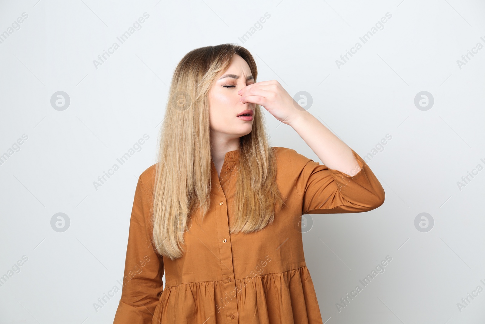 Photo of Young woman suffering from runny nose on white background