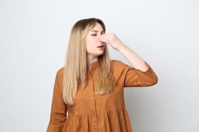 Young woman suffering from runny nose on white background