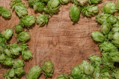 Frame of fresh green hops on wooden table, flat lay. Space for text