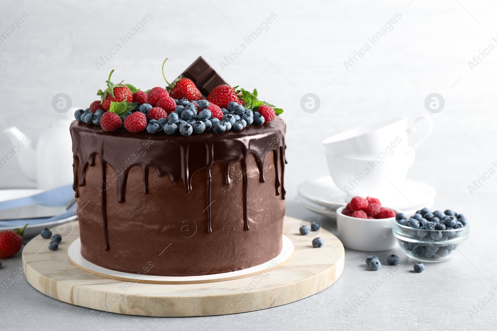 Photo of Freshly made delicious chocolate cake decorated with berries on white table