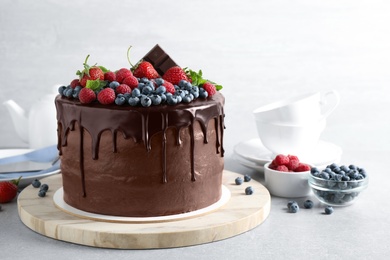 Freshly made delicious chocolate cake decorated with berries on white table