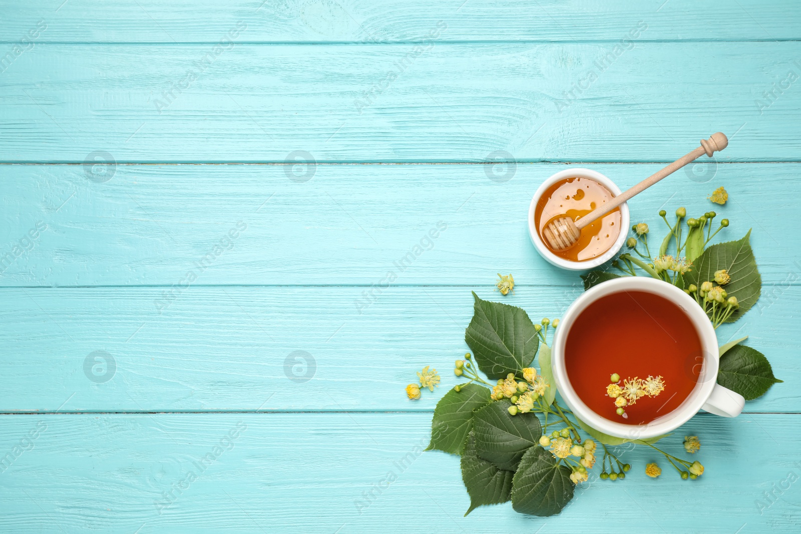 Photo of Flat lay composition with tea and linden blossom on light blue wooden table. Space for text