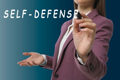 Image of Woman writing words Self Defense with marker on glass board against blue gradient background, closeup