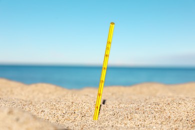 Photo of Yellow weather thermometer in sand near sea