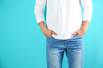 Young man in stylish jeans on color background