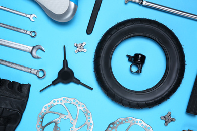 Photo of Set of different bicycle tools and parts on light blue background, flat lay