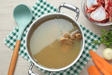 Delicious homemade bone broth and ingredients on white wooden table, flat lay