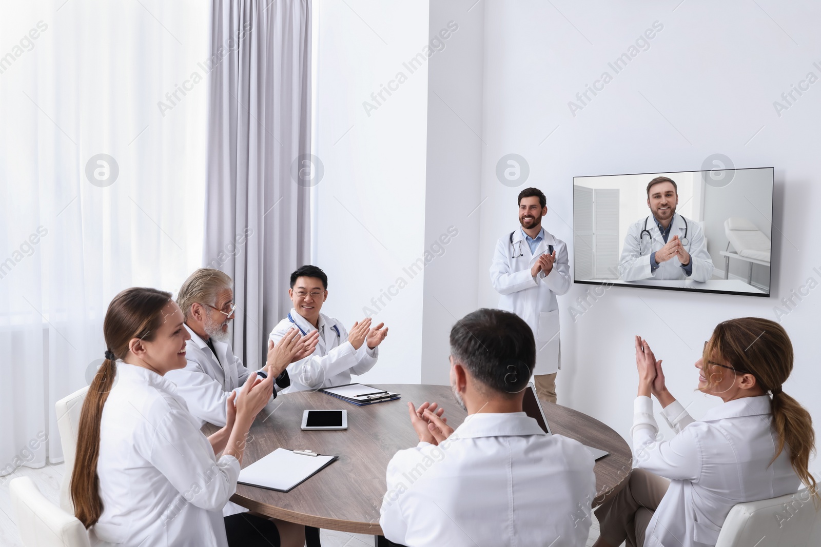 Image of Lecture with online participant. Doctors in meeting room. Using tv for videoconference