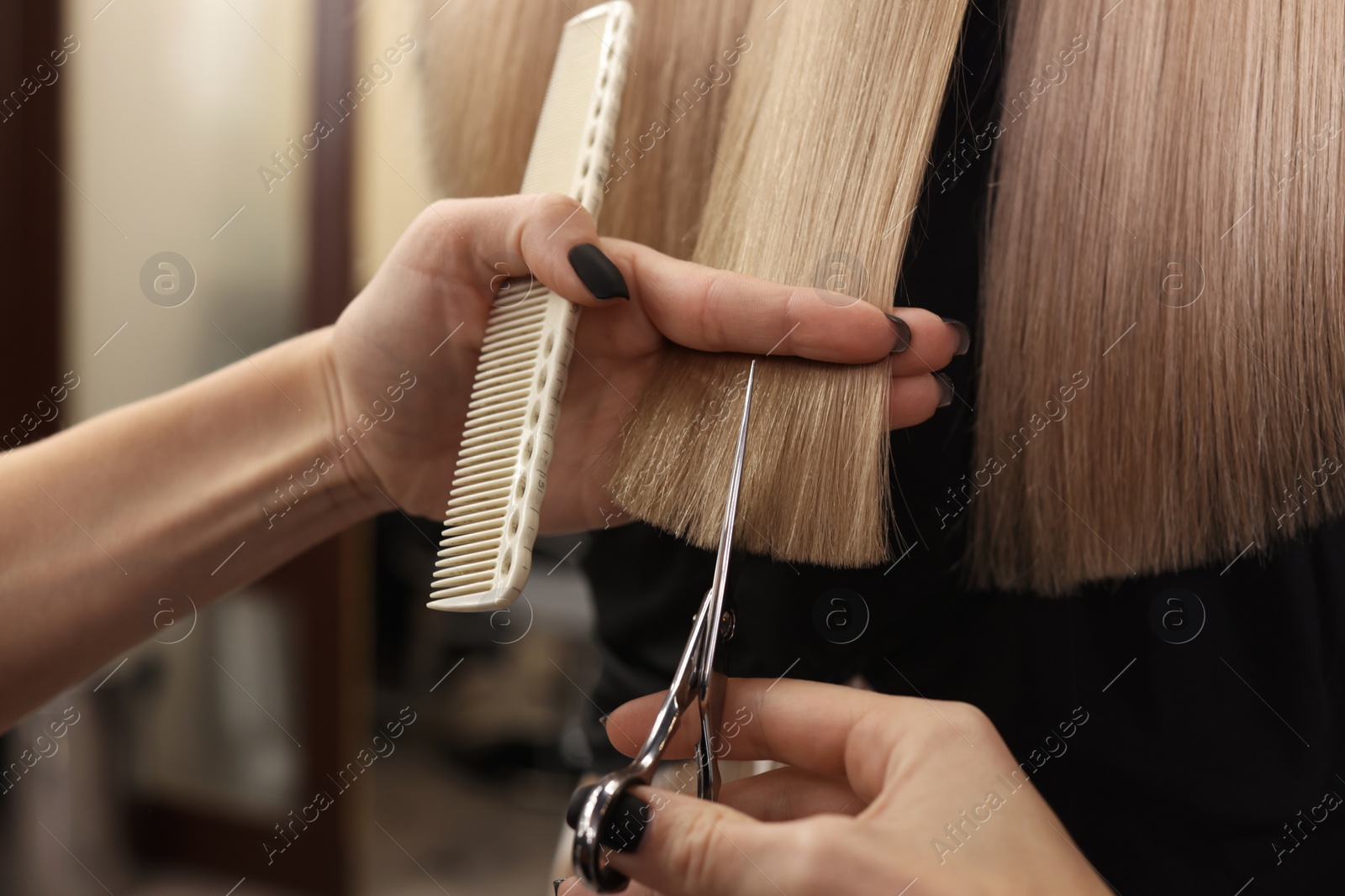 Photo of Professional hairdresser cutting woman's hair in salon, closeup