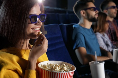 Young woman with popcorn watching movie in cinema