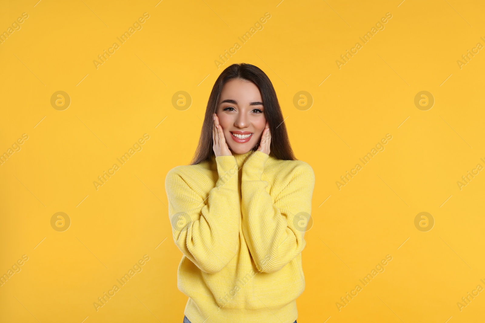 Photo of Beautiful young woman wearing warm sweater on yellow background