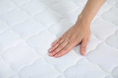 Photo of Woman touching soft white mattress, closeup view