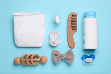 Flat lay composition with pacifiers and other baby stuff on light blue background