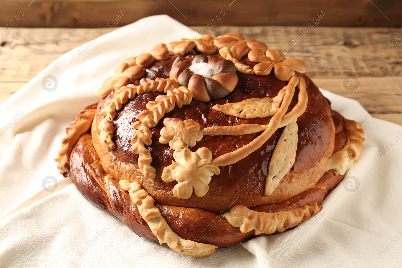 Photo of Korovai on tablecloth, closeup. Ukrainian bread and salt welcoming tradition