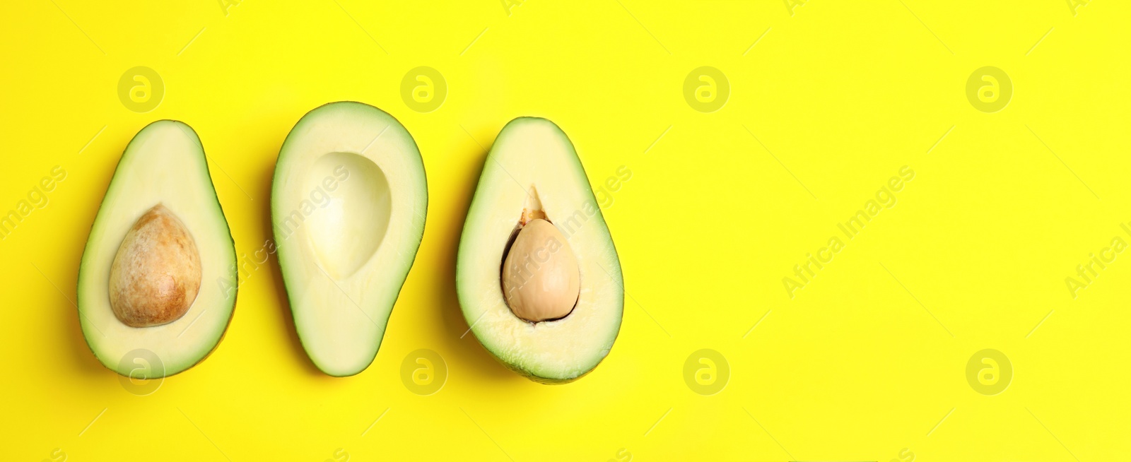 Image of Cut fresh ripe avocados and space for text on yellow background, flat lay. Banner design