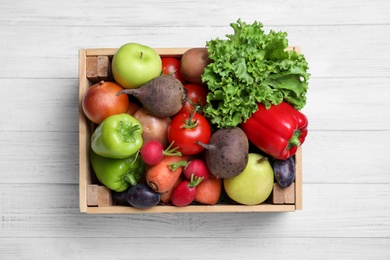 Crate full of different vegetables and fruits on white wooden table, top view. Harvesting time