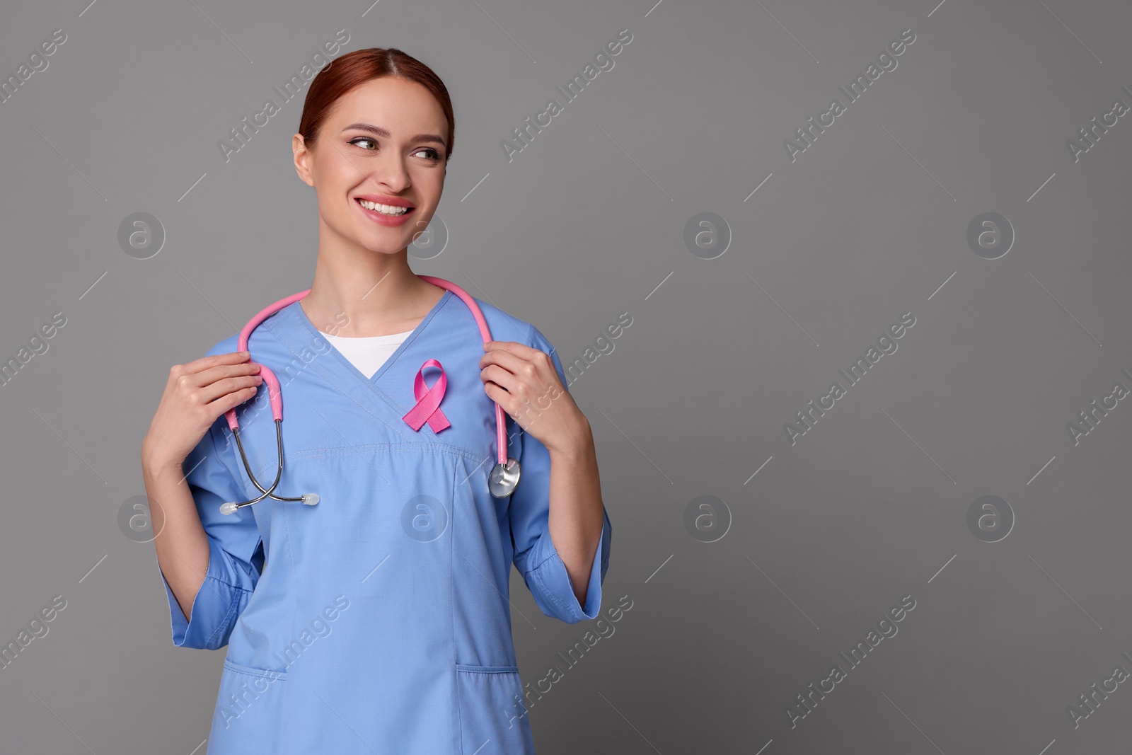 Photo of Mammologist with pink ribbon on gray background, space for text. Breast cancer awareness