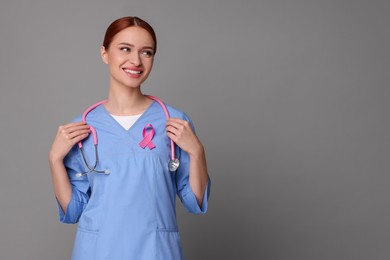 Photo of Mammologist with pink ribbon on gray background, space for text. Breast cancer awareness