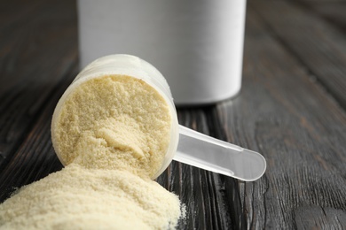 Photo of Overturned scoop of protein powder on black wooden table