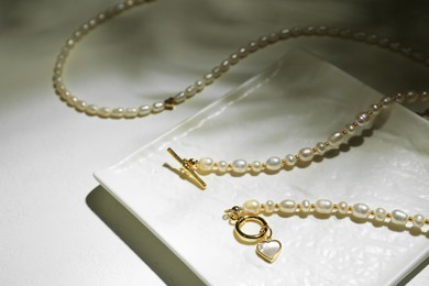 Photo of Elegant pearl necklaces on white background. Stylish jewelry