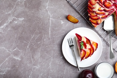 Slice of delicious cake with plums on grey marble table, flat lay. Space for text