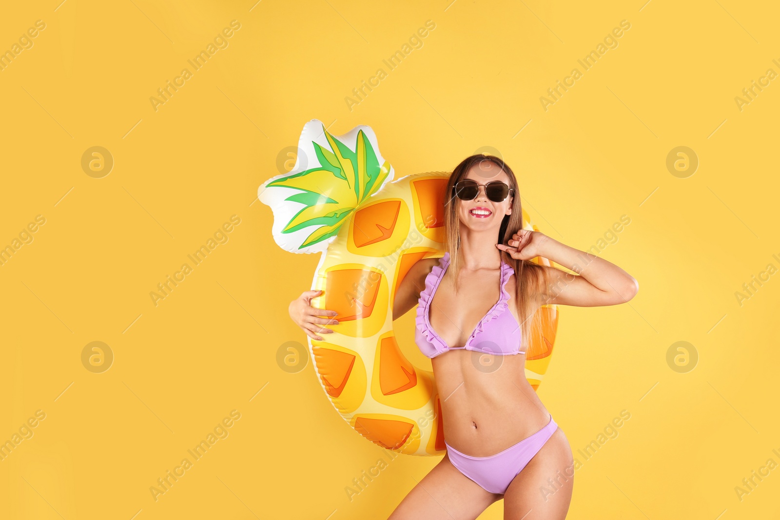 Photo of Pretty sexy woman in stylish bikini with inflatable ring on color background