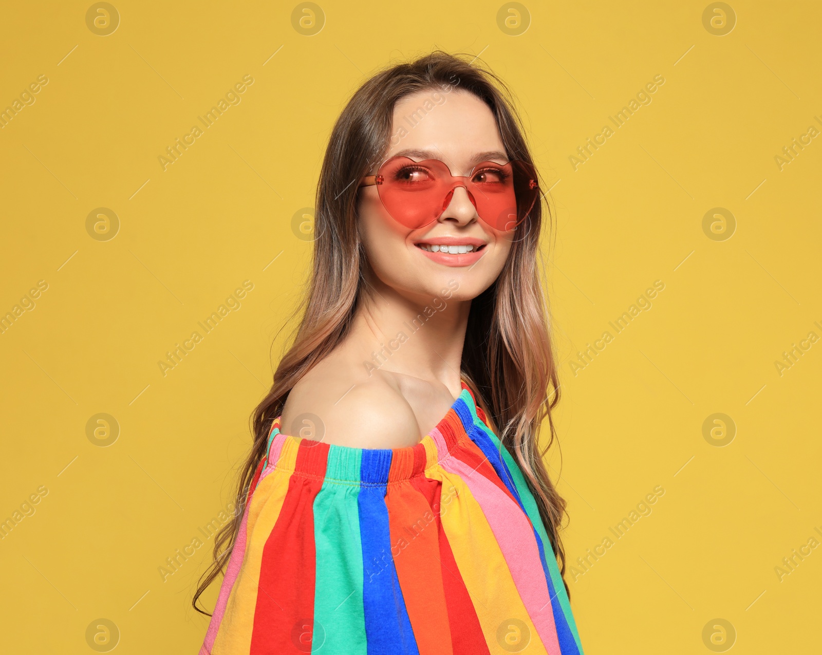 Photo of Portrait of beautiful young woman with heart shaped sunglasses on color background