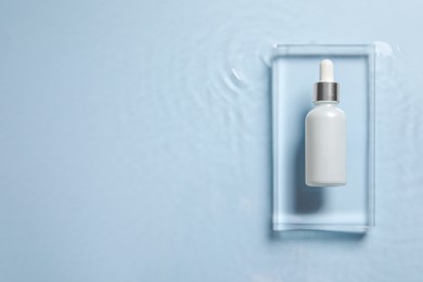 Photo of Bottle of cosmetic serum and water on light blue background, top view. Space for text