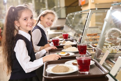 Children near serving line with healthy food in school canteen