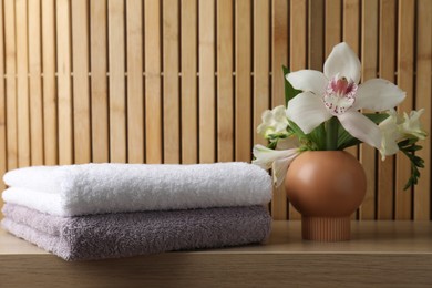 Photo of Terry towels and beautiful flowers on wooden table
