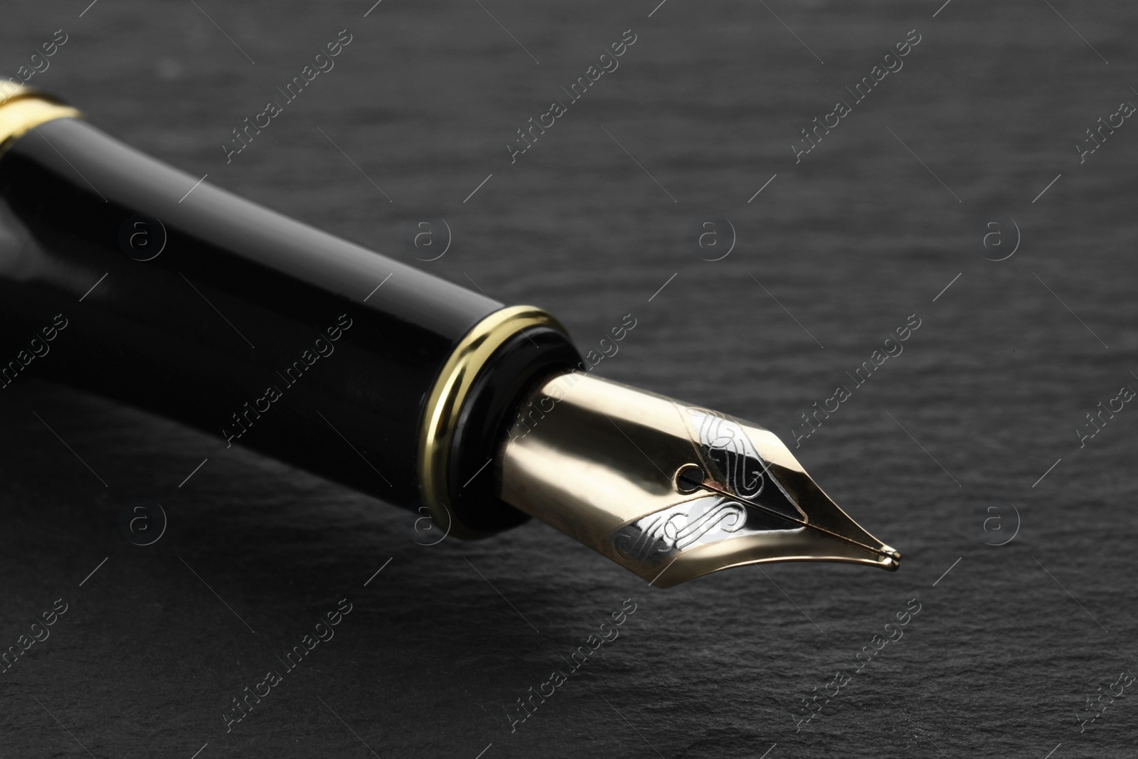 Photo of Stylish fountain pen on dark textured table, closeup