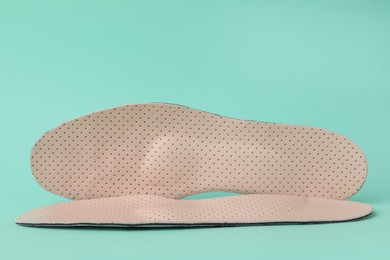 Photo of Beige comfortable orthopedic insoles on turquoise background