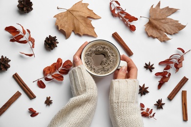 Woman with cup of hot drink on white background, top view. Cozy autumn atmosphere