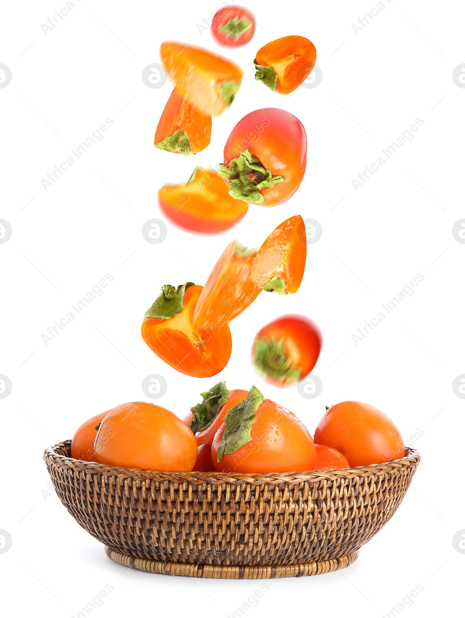 Image of Sweet ripe persimmons falling into bowl on white background