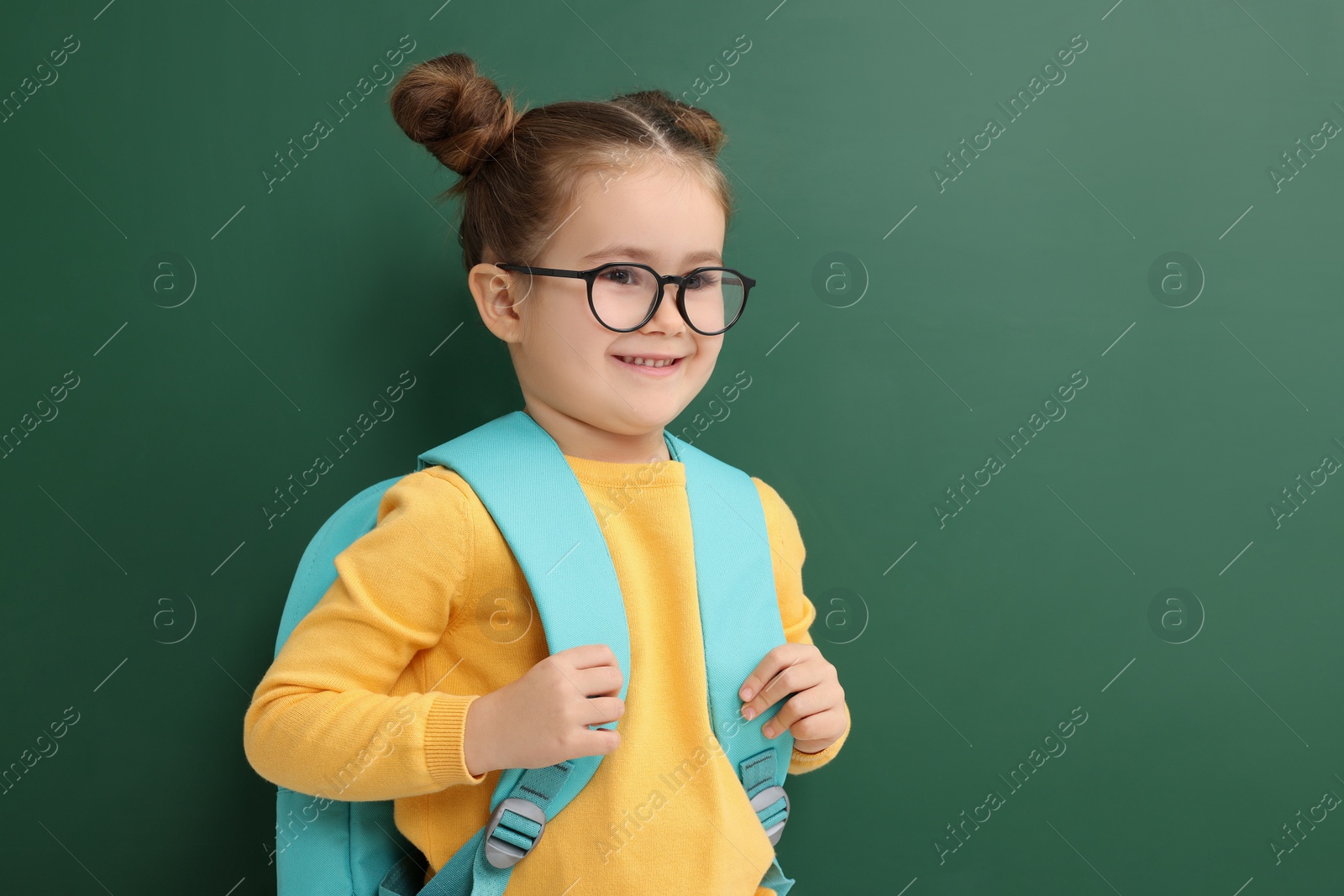 Photo of Happy little school child with backpack near chalkboard. Space for text