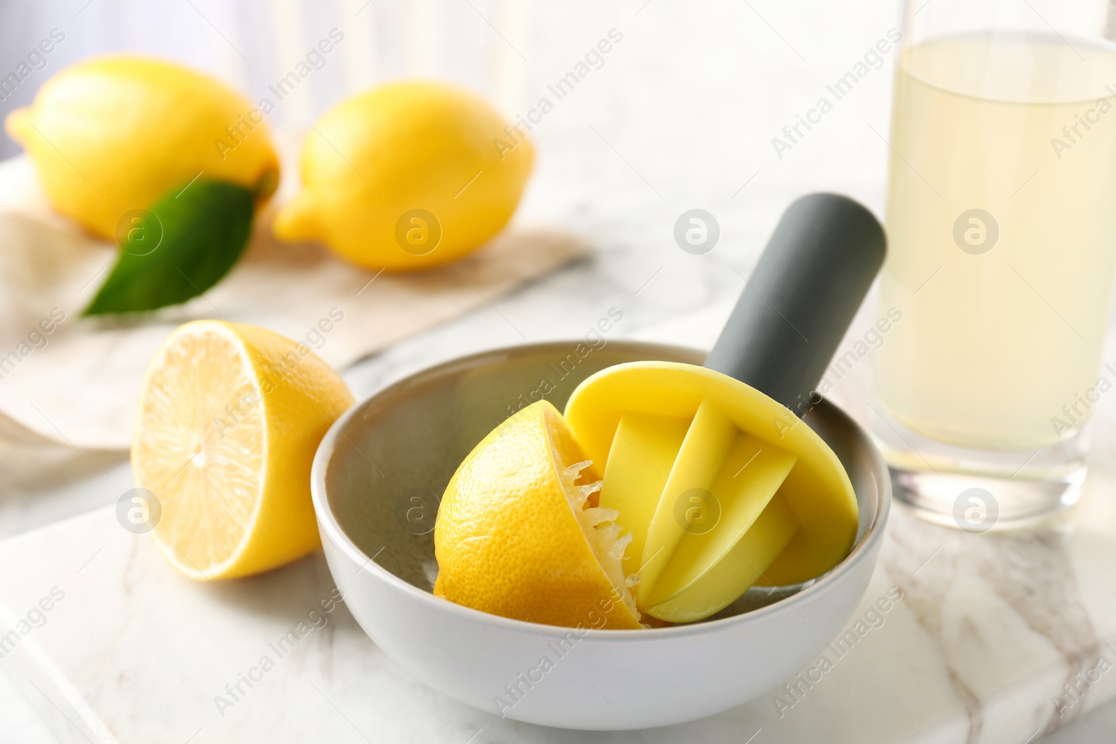 Photo of Plastic citrus squeezer with lemon half in bowl on table