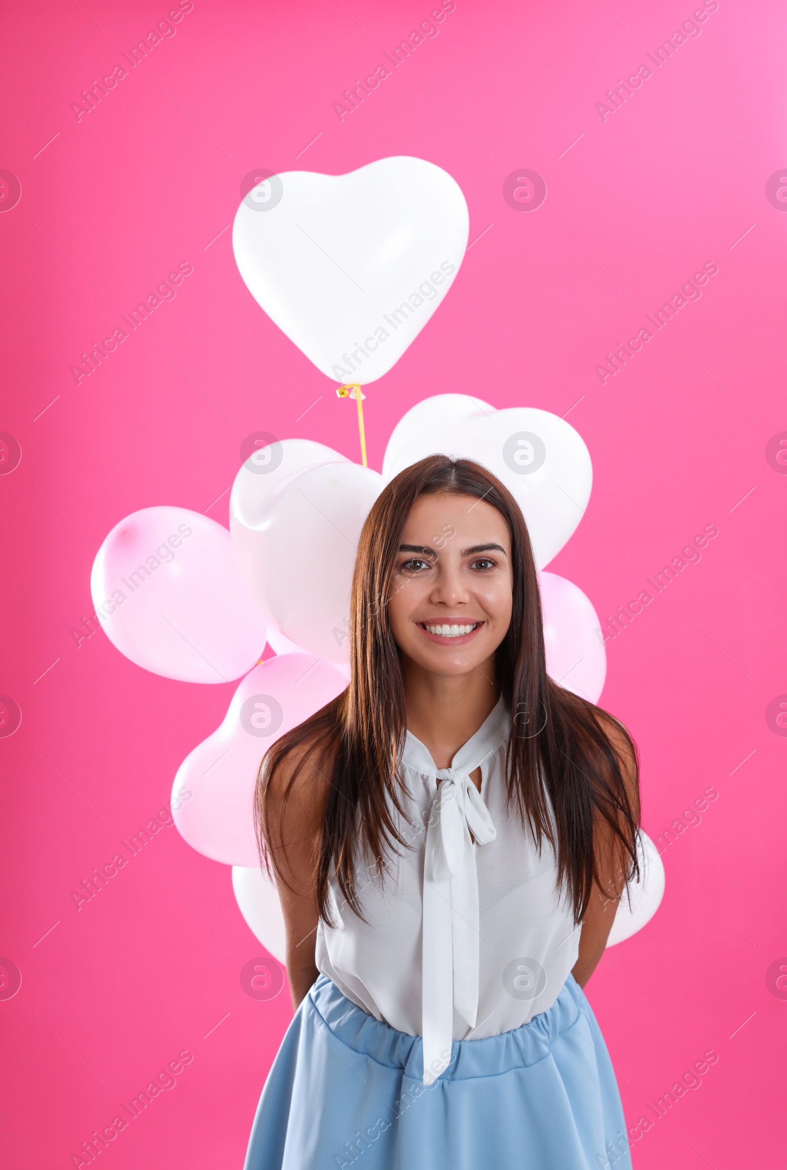 Photo of Young woman with air balloons on pink background. Celebration of Saint Valentine's Day