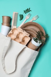 Photo of Eco bag with different disposable items on turquoise background, flat lay. Recycling concept