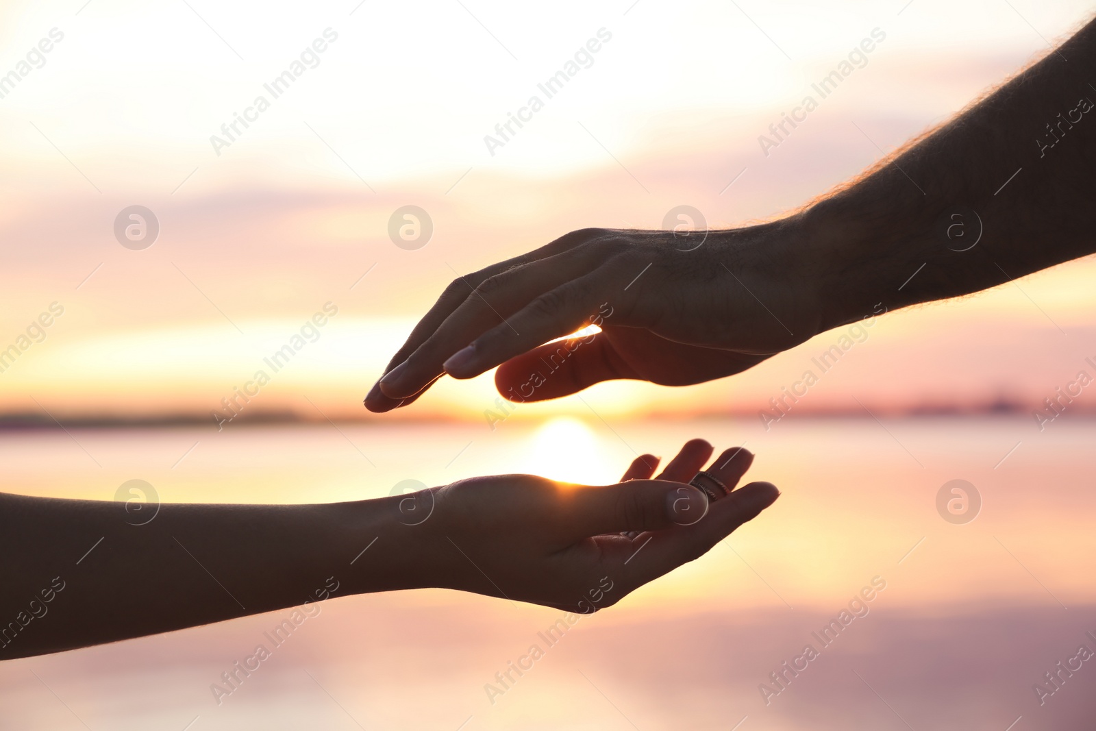 Photo of Man and woman reaching hands to each other at sunset, closeup. Nature healing power