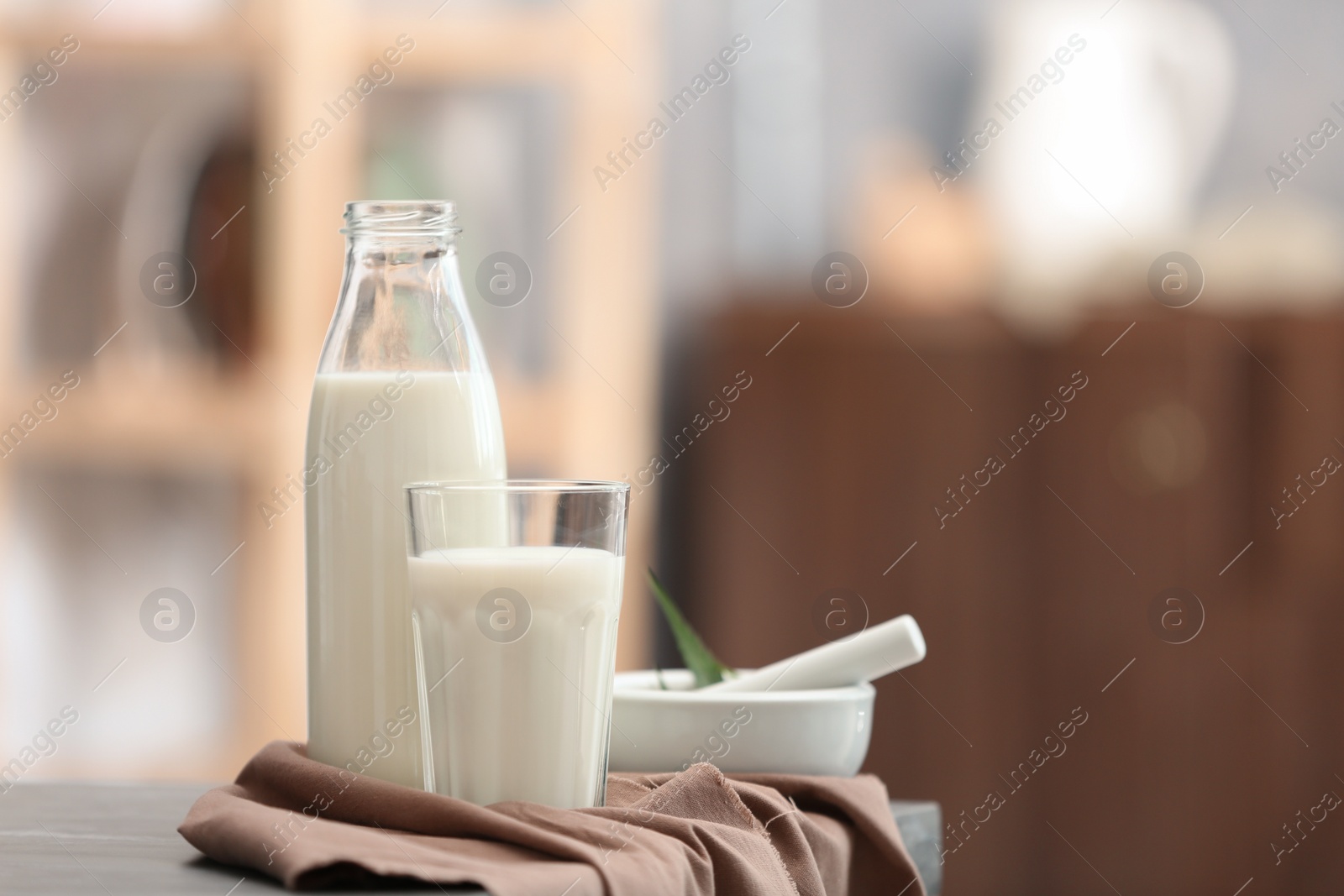 Photo of Glass and bottle with hemp milk on table against blurred background