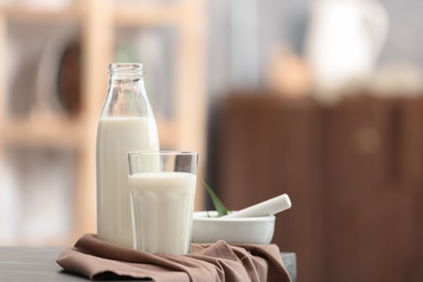 Glass and bottle with hemp milk on table against blurred background