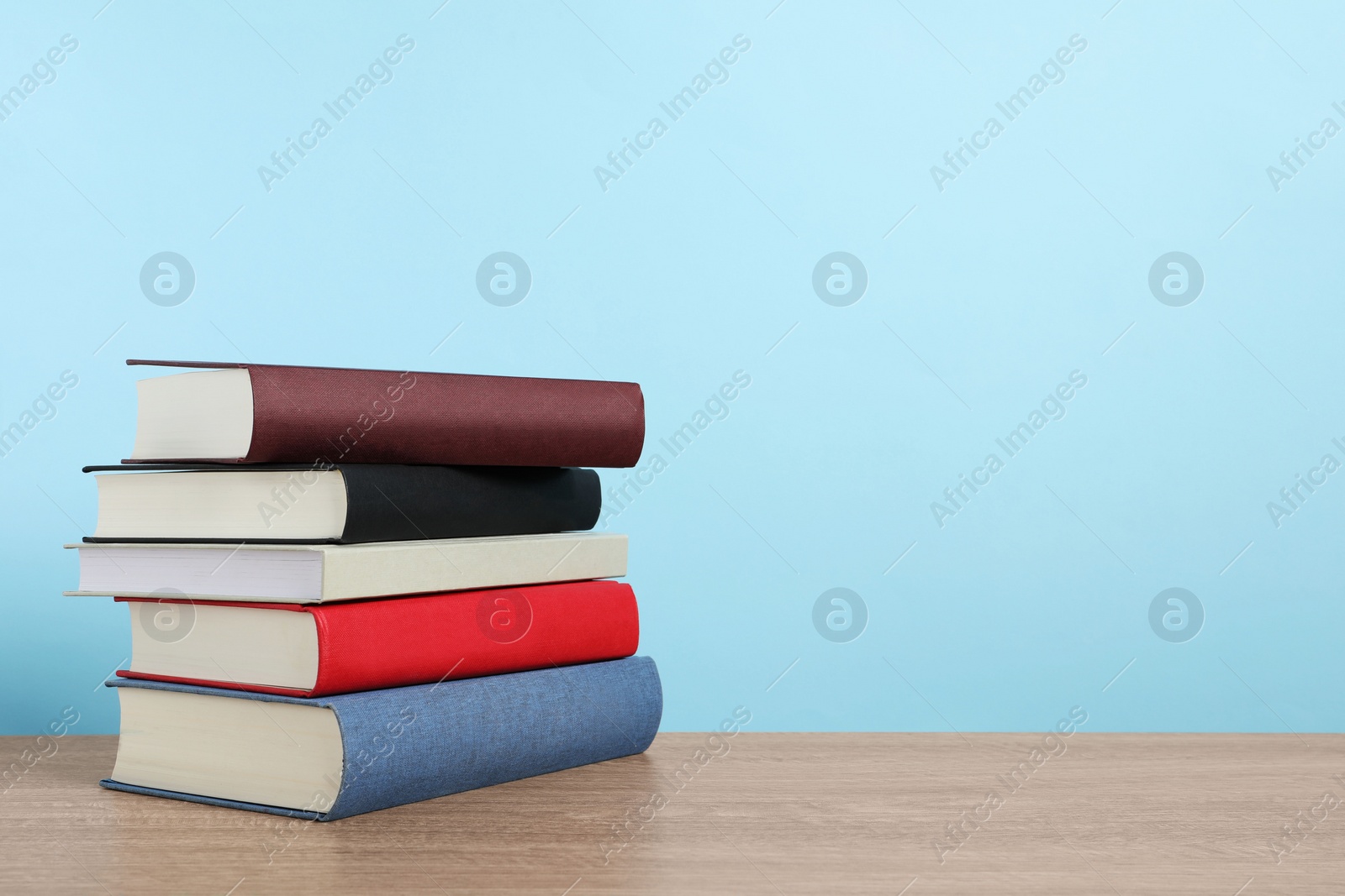 Photo of Stack of hardcover books on wooden table, space for text