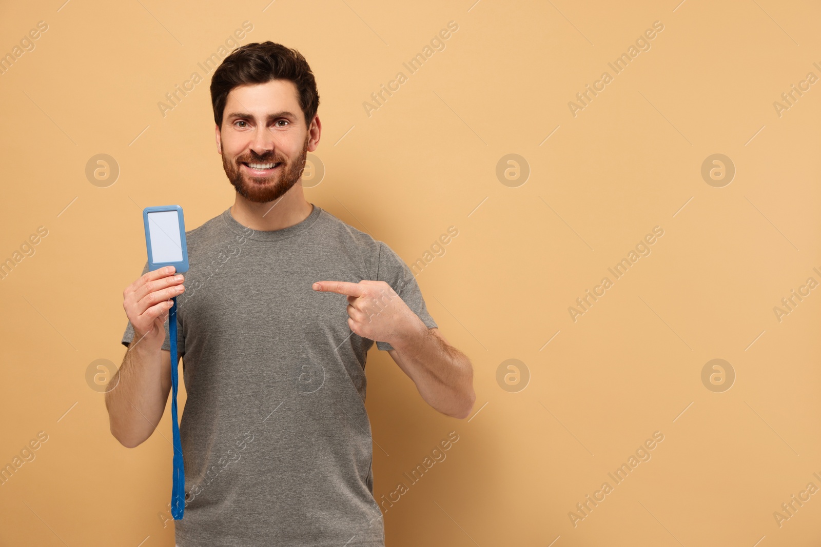 Photo of Happy man showing VIP pass badge on beige background, space for text